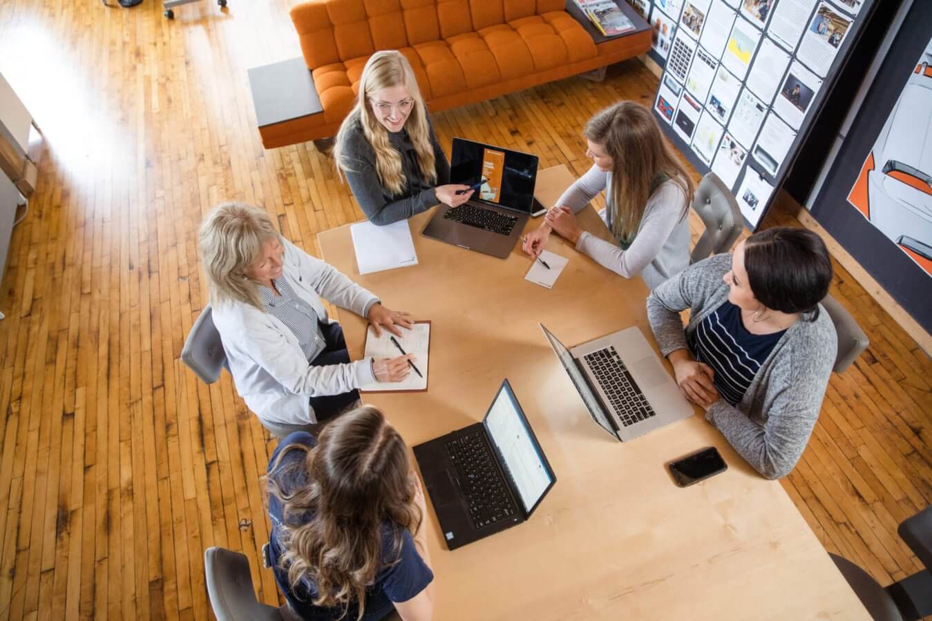 A group of females in a meeting look at designs on a computer