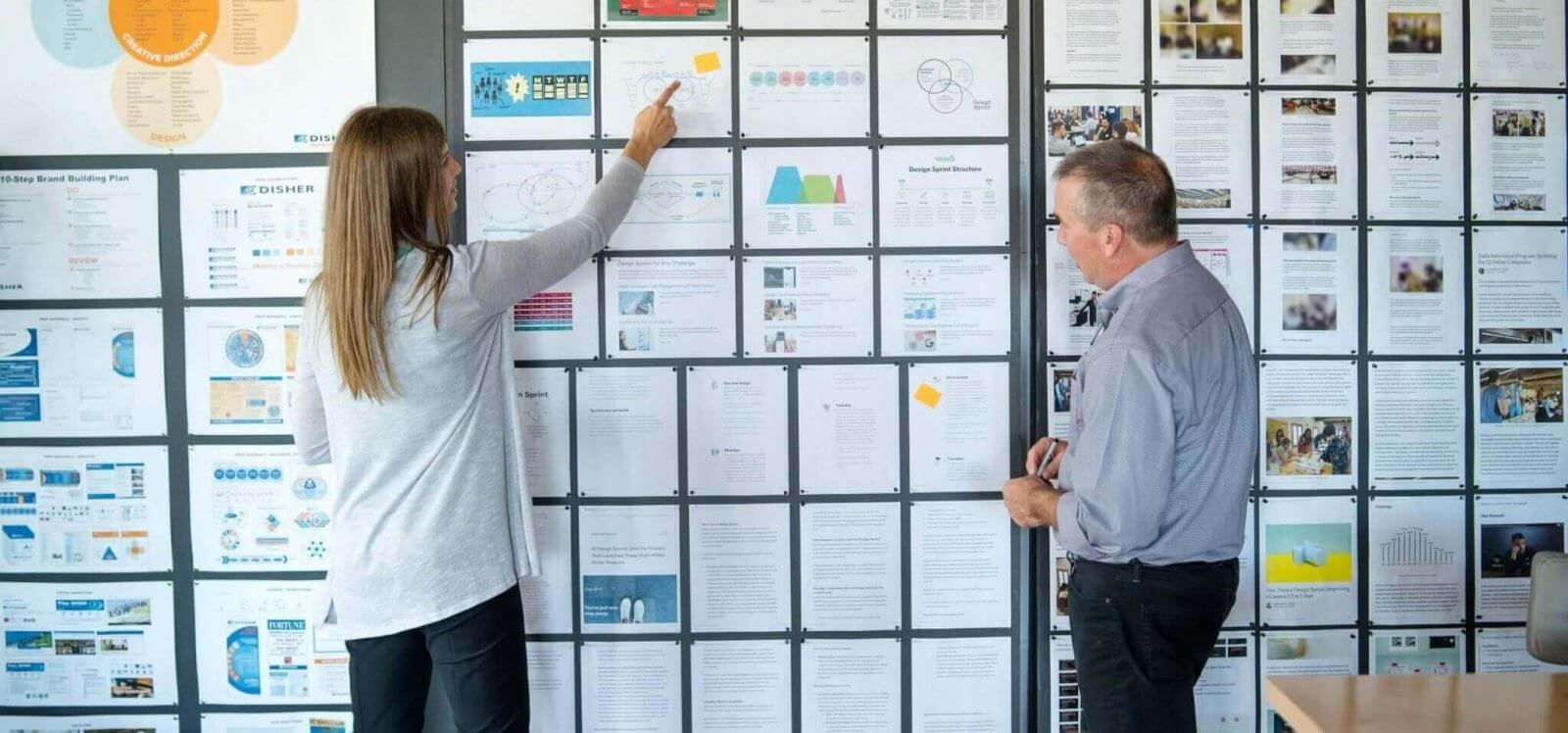 A woman talking with a man and pointing to innovative research boards
