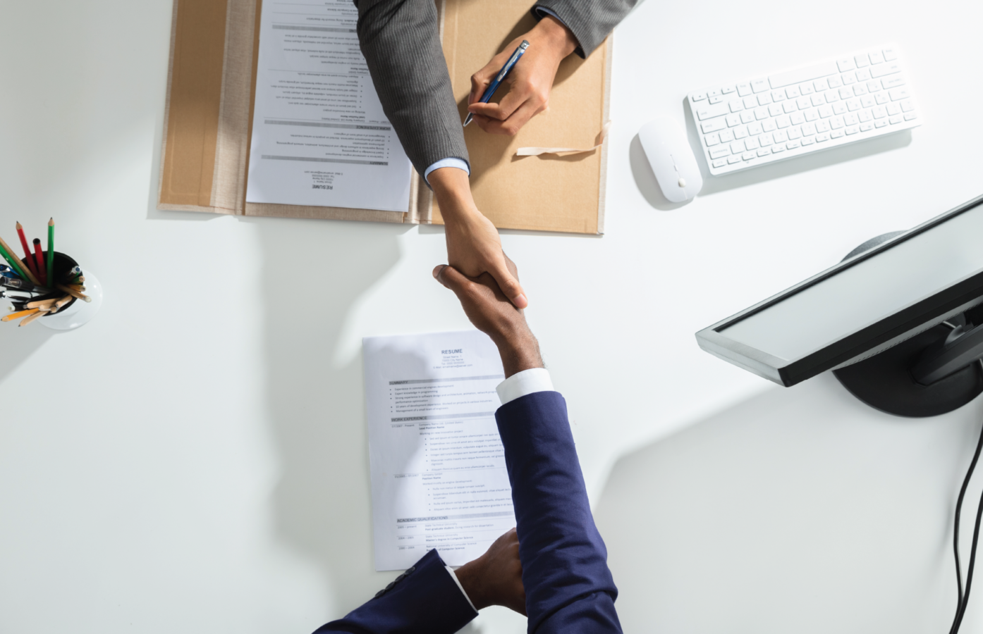 Two people shaking hands over a desk