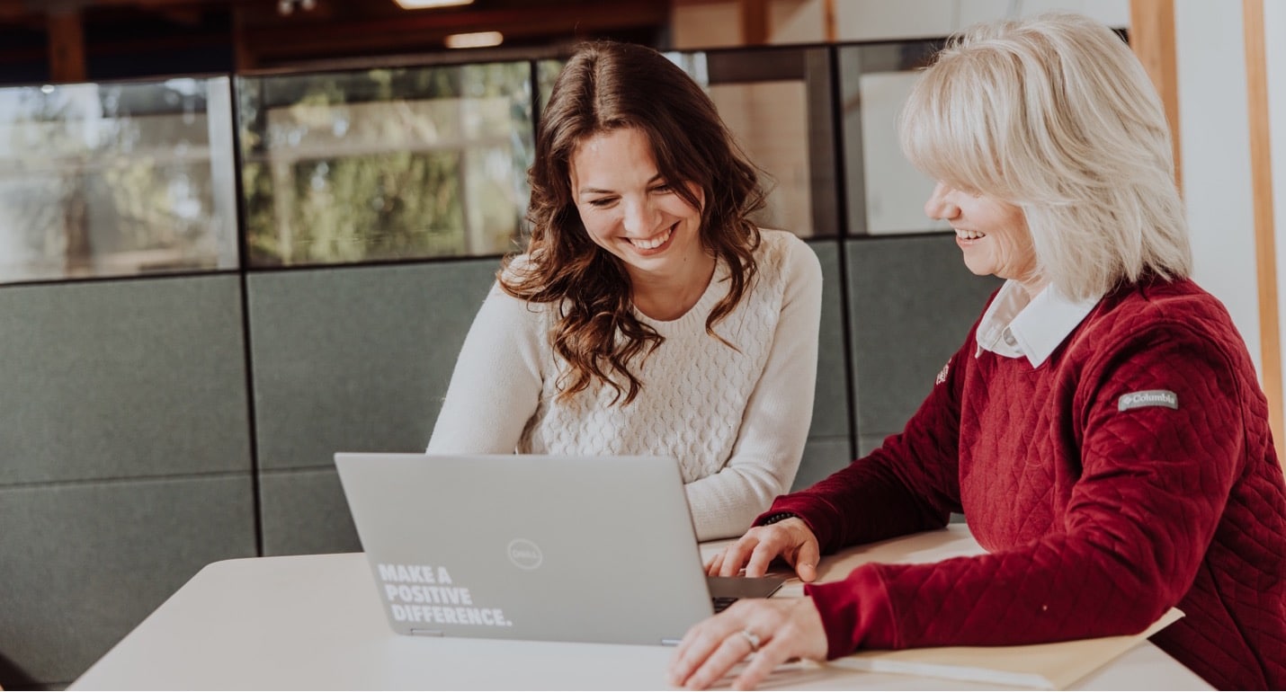 Two recruiters look together at a laptop