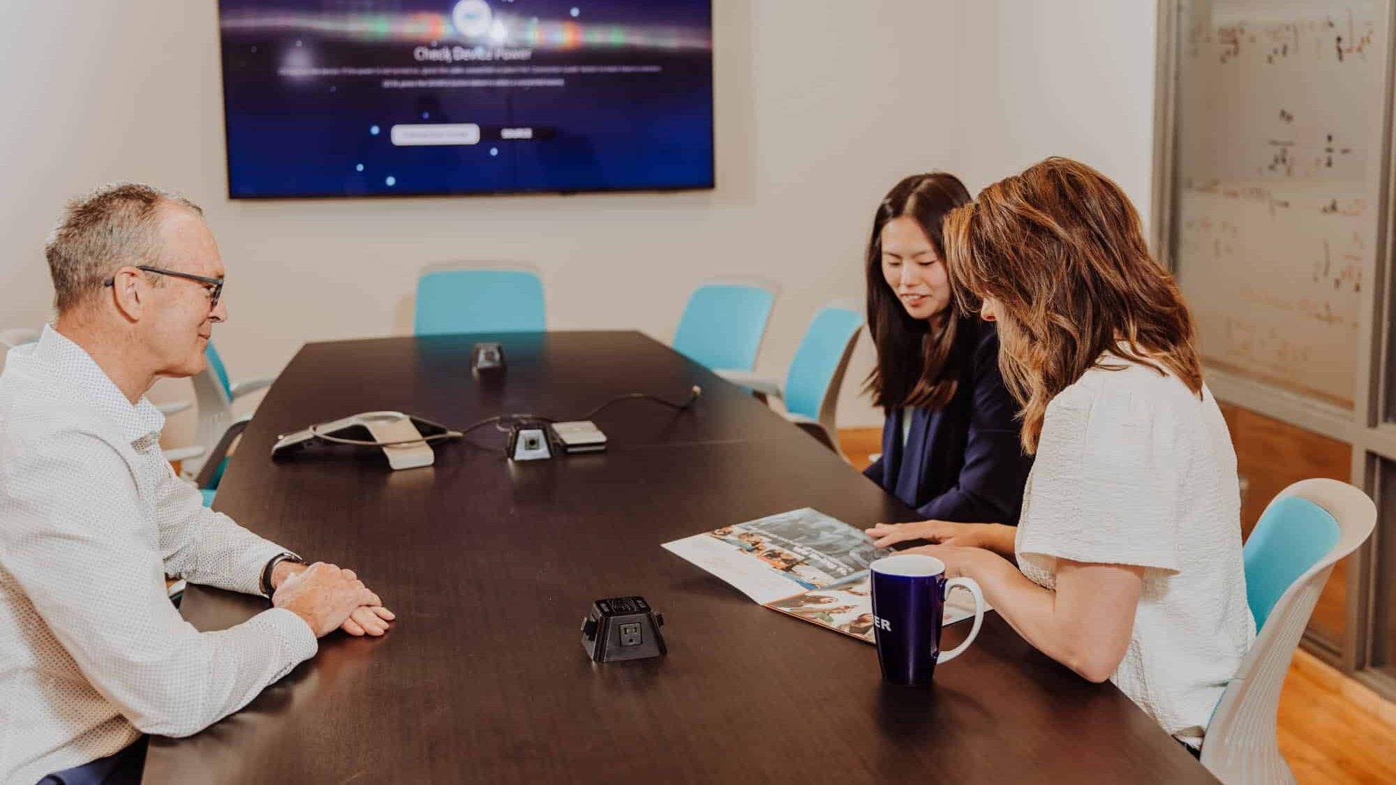 Two recruiters sit with a customer discussing their talent brand
