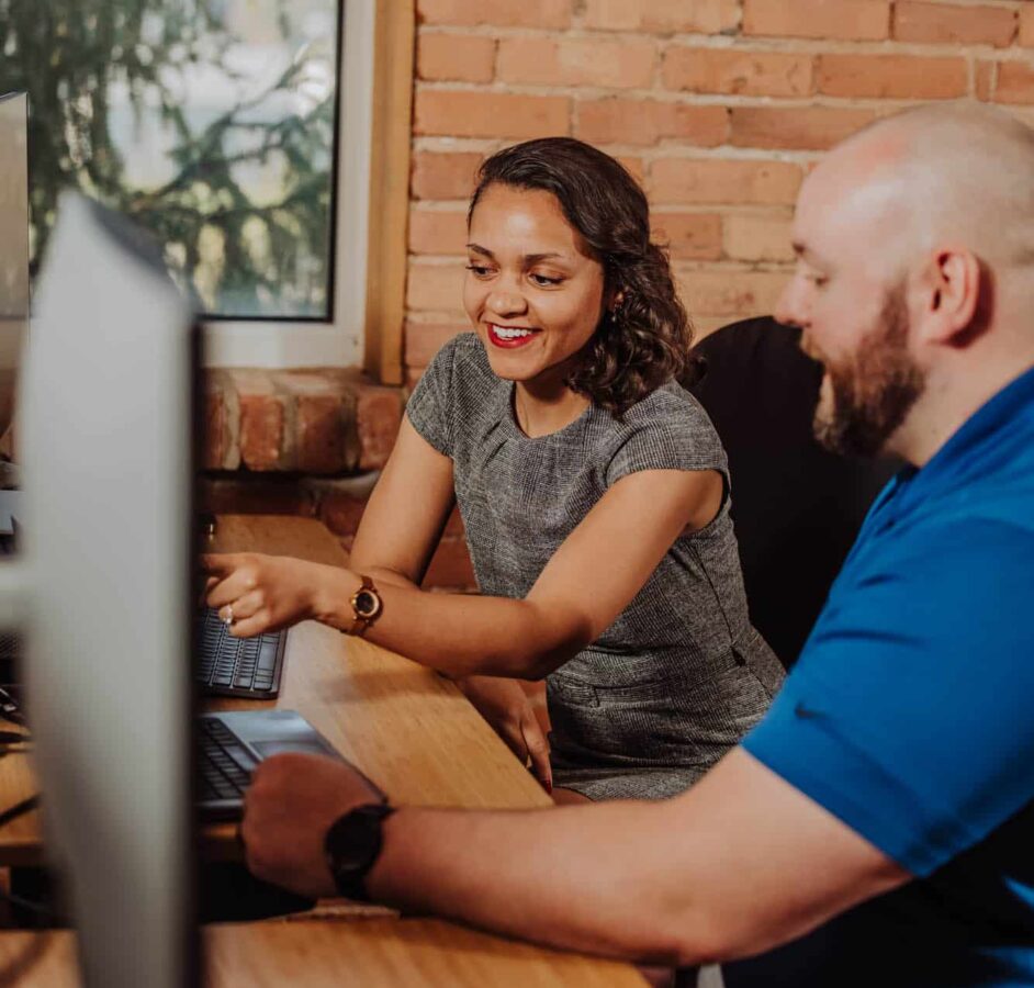 Two talent recruiters looking at a computer discussing talent brand