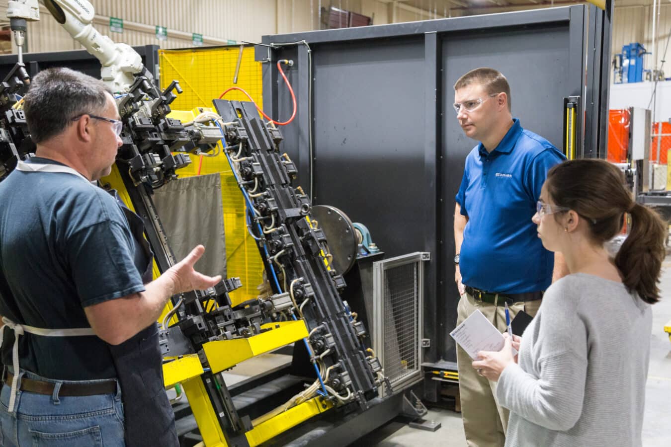 A manufacturing engineer inspects a machine in a manufacturing plant