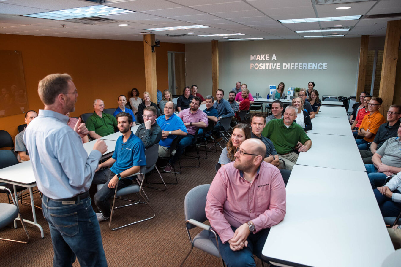 A DISHER leader stands in front of a team meeting.